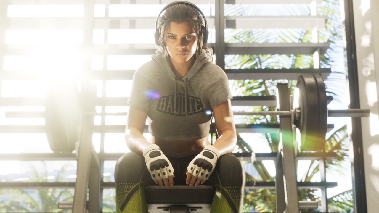 Lucia seated on a gym bench with headphones and training gloves.